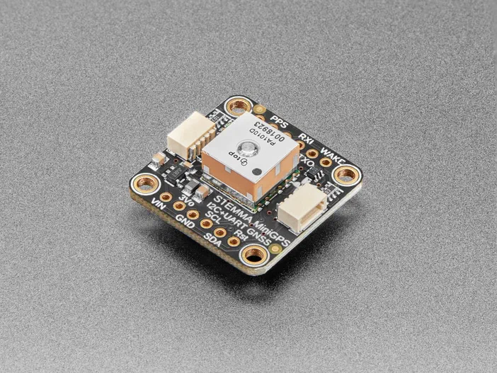 Module GPS PA1010D d'Adafruit avec connecteurs STEMMA et étiquettes de broches visibles sur fond gris.