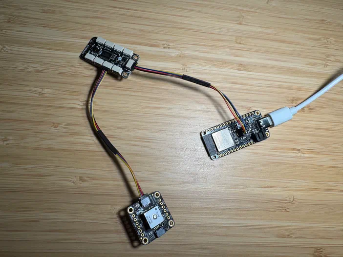 Trois modules électroniques connectés par des câbles multicolores sur une surface en bois clair.
